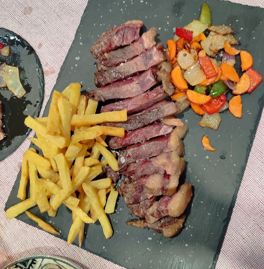 Chuletón a la brasa fileteado, con patatas fritas y verduras salteadas